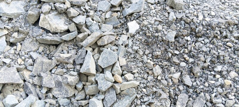 Bulk crushed mountain stones texture. High-quality aggregate gravel for industrial concrete mixing and highway foundation construction
