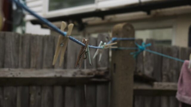 Close up of plastic clothespins on a blue washing line with old wooden fence background