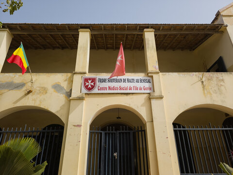 May 2026, Gor&eacute;e, S&eacute;n&eacute;gal. Historic yellow facade of the Sovereign Order of Malta medical and social center on Gor&eacute;e Island, Senegal, featuring colonial architecture, arched entrances, waving flags.