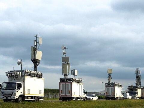 View of mobile telecommunication trucks with antennas and satellite dishes parked in a grassy field under a cloudy sky in Besiktas, Istanbul, Turkey.