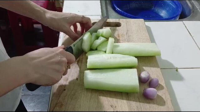 Hands Cutting Winter Melon into Thin Slices for Dinner Preparation