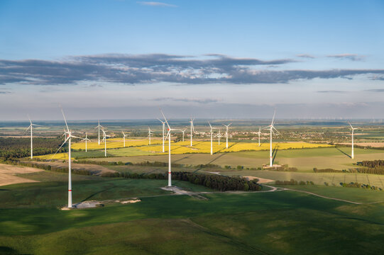 Aerial view of a large wind farm spread across agricultural land in Germany. Modern wind turbines produce renewable electricity while coexisting with farmland and rural communities.
