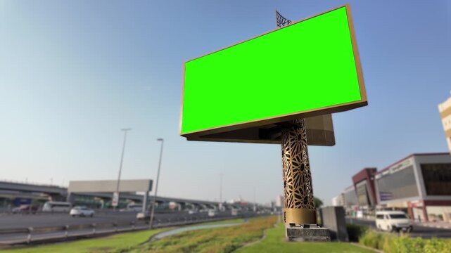 Green billboard on Sheikh Zayed Road, Dubai highway with traffic and modern buildings.