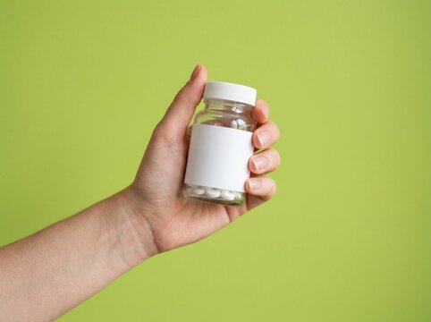 Hand Holding Clear Glass Pill Bottle with Blank Label and White Pills