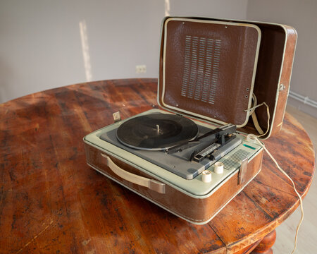 Vintage record player on a rustic round table, open lid.