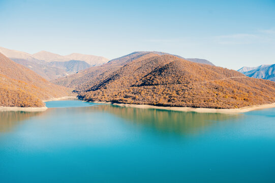 Turquoise lake mirrors mountains beneath clear sky