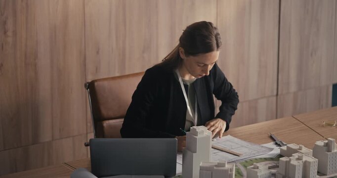 A woman focuses on building a model while sitting at her desk in a bright office