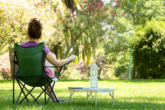 Woman relaxing in camping chair with drink in park
