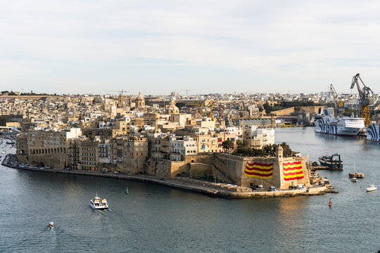 View of the historic fortifications of Senglea with large flags on the bastions and the Gardjola watchtower overlooking the Grand Harbour in Valletta, Port Region, Malta.