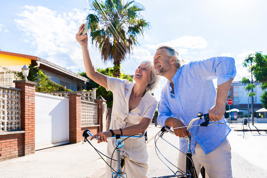 Beautiful happy senior couple dating at the seaside and cycling