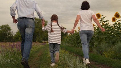 Fototapeta premium Happy family walking in nature, Parents and child enjoying a summer day, Family adventure in a sunflower field, Childhood memories in the countryside, Outdoor family time together, Nature walk with