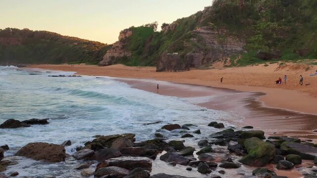 Sydney, Australia - This clip features a scenic coastal landscape on Sydney&rsquo;s Northern Beaches, where gentle waves wash over shoreline rocks beside a sandy beach. 