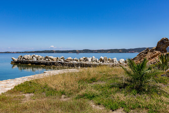 Small rock wall next to the water and a beach, Ammoulliani, Greece