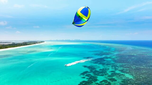 Colorful kite surfer gliding over beautiful turquoise tropical ocean water on a sunny day