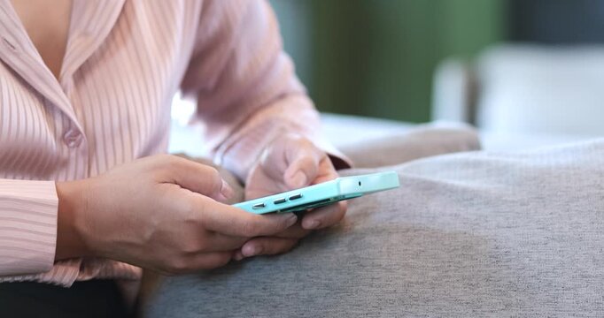 Woman using smartphone while sitting on sofa at home. copy space, online communication, mobile banking, digital technology, social media, and modern lifestyle, close-up