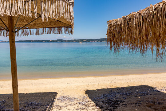 There are two umbrellas on the beach near the water, Ammoulliani, Greece