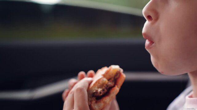 Roadside meal for a young traveler, Girl s lunchtime adventure in the backseat, Traveling with kids and snacks, Smiling girl savoring her burger, Quick food break during family travel, Childhood road