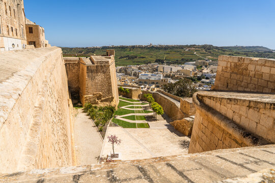 View of the historic stone fortifications with green gardens and a panoramic view of the surrounding landscape and town in Zebbug, Gozo Region, Malta.