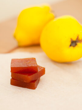 Authentic spanish dulce de membrillo jelly with fresh organic quince fruits for gourmet snack on parchment paper background. Close up.