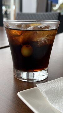 Glass of red vermouth with green olives and orange slice