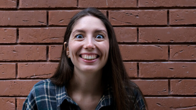 A surprised, delighted woman. An impressed woman tries to attract attention. Sales concept, a compelling offer. An enthusiastic girl against a brick wall.