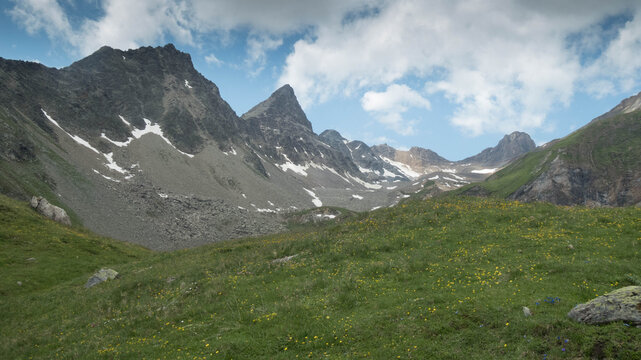 Majestic rocky mountain peaks under a dramatic blue sky with fast-moving white clouds, high alpine landscape in the Loetschental valley, Valais, Switzerland.