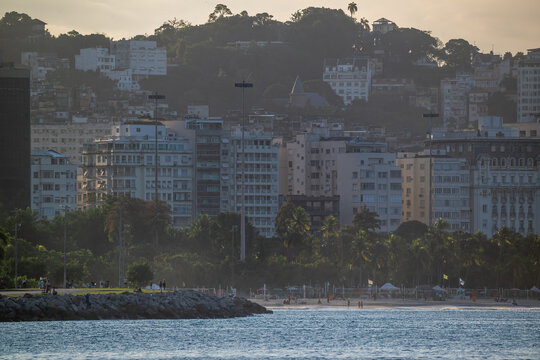 View of Aterro do Flamengo park featuring lush greenery, city buildings, and a rocky shoreline at dusk in Rio de Janeiro, Rio de Janeiro, Brazil.