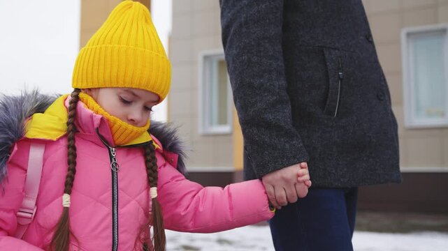 father leads girl daughter school walking along winter road, child kid girl daughter holds father hand way school, school children bag, road school, girl goes class lesson, educational children