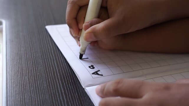 Close-up of parent and child hands practicing writing together with a marker on a notebook, hand-over-hand guidance for early learning and motor skill development