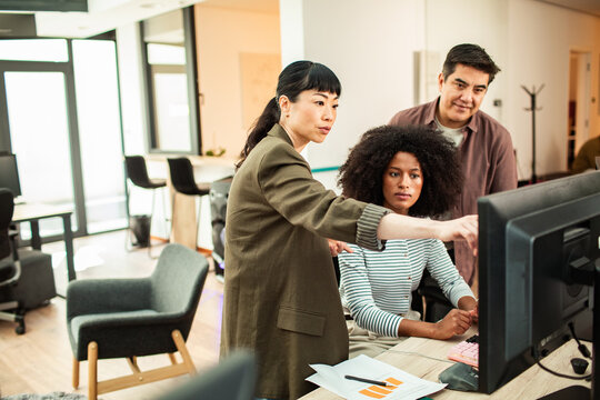 Coworkers collaborating at computer in modern office