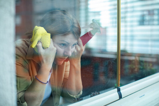 Tired woman cleaning apartment window at home