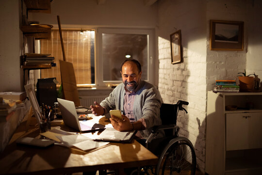 Smiling man in wheelchair on video call at home office