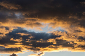 Obraz premium Dramatic storm clouds illuminated by golden sunset light