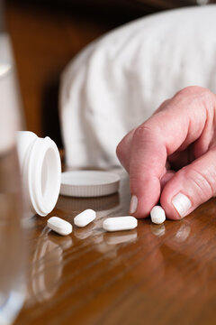 Person taking medication, picking up pill from nightstand