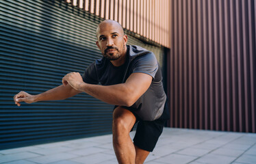 Fototapeta premium Handsome sportive man in athletic wear doing workout exercise, athlete enjoying an outdoor run session in city, fitness motivation and urban wellness