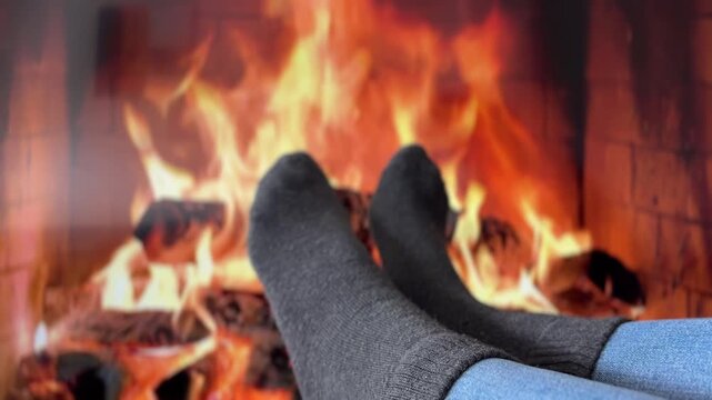 Pies con calcetines frente a chimenea en oto&ntilde;o