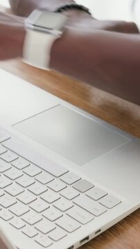 Vertical video: Starting work hands typing at desk on laptop checking watch resting arm