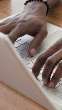 Vertical video: Preparing hands moving into view then typing at desk, working on laptop with watch
