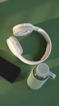Vertical video: Rotating camera revealing headset on green mat, documenting phone and water bottle