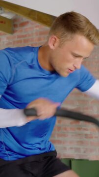 Vertical video: Reacting to bars moving, man gripping bike, pedaling for cardio at home in blue top
