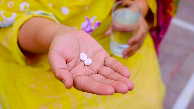 Person holding white pills and water glass for medication dosage healthcare treatment pharmaceutical dosing health healthcare treatment 