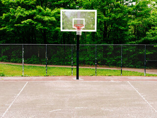 Naklejka premium Terrain de basket avec filet et arbres verts en arrière-plan, photo prise en extérieur