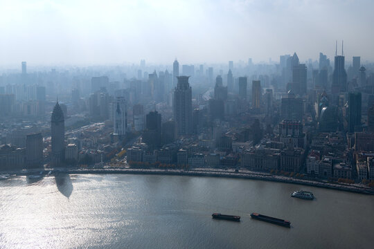 View of the Bund waterfront and the dense urban skyline with skyscrapers along the Huangpu River under a hazy sky Shanghai, Shanghai, China.