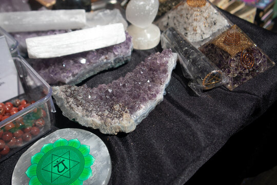 Collezione di cristalli e minerali per cristalloterapia esposti su un tavolo con un grande geode di ametista viola e piramidi in orgonite