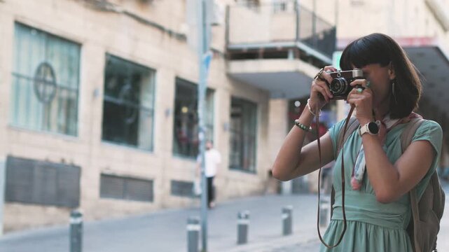 Close-up of a dark-haired woman holding a vintage camera near her face, looking through the viewfinder with focused expression. girl with a camera.