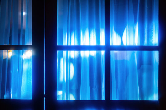 View of blue curtains behind a window frame with bright lights and bokeh effects in the background Rio de Janeiro, State of Rio de Janeiro, Brazil.