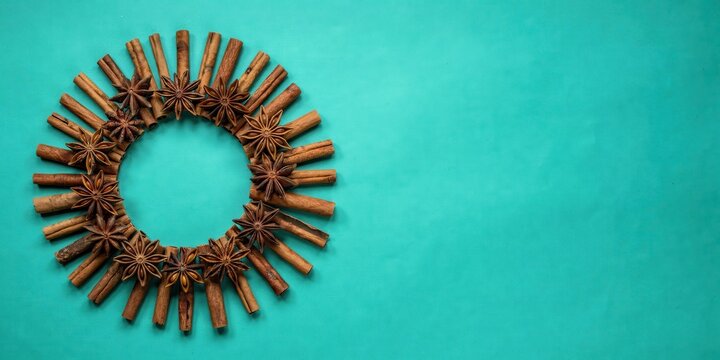 A creative arrangement of cinnamon sticks forms a circular pattern on a vibrant teal background.