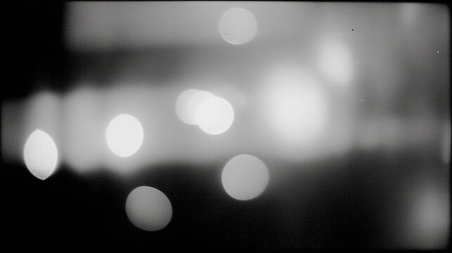 blurred black and white bokeh abstract background with light spots and grain texture