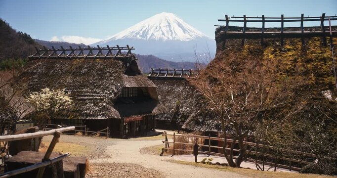 Little boy and man walking on path of ancient Japanese village with Mt. Fuji in distance