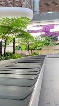 Baggage conveyor belt at Changi Airport Singapore. Vertical footage. Empty baggage claim area with curved conveyor inside modern airport terminal